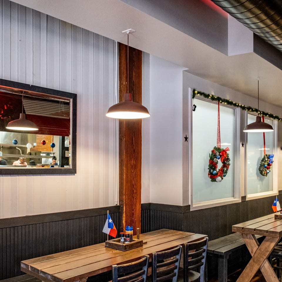Interior of Moak's Family Texas BBQ with wooden tables, benches, and festive wreaths.