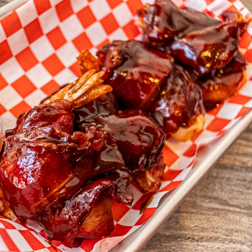 Moak's Family Texas BBQ chicken wings coated in a rich, dark barbecue sauce on red and white checkered paper.